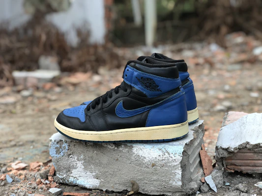 Stylish streetwear sneakers in black and blue tones, positioned on a concrete city sidewalk.