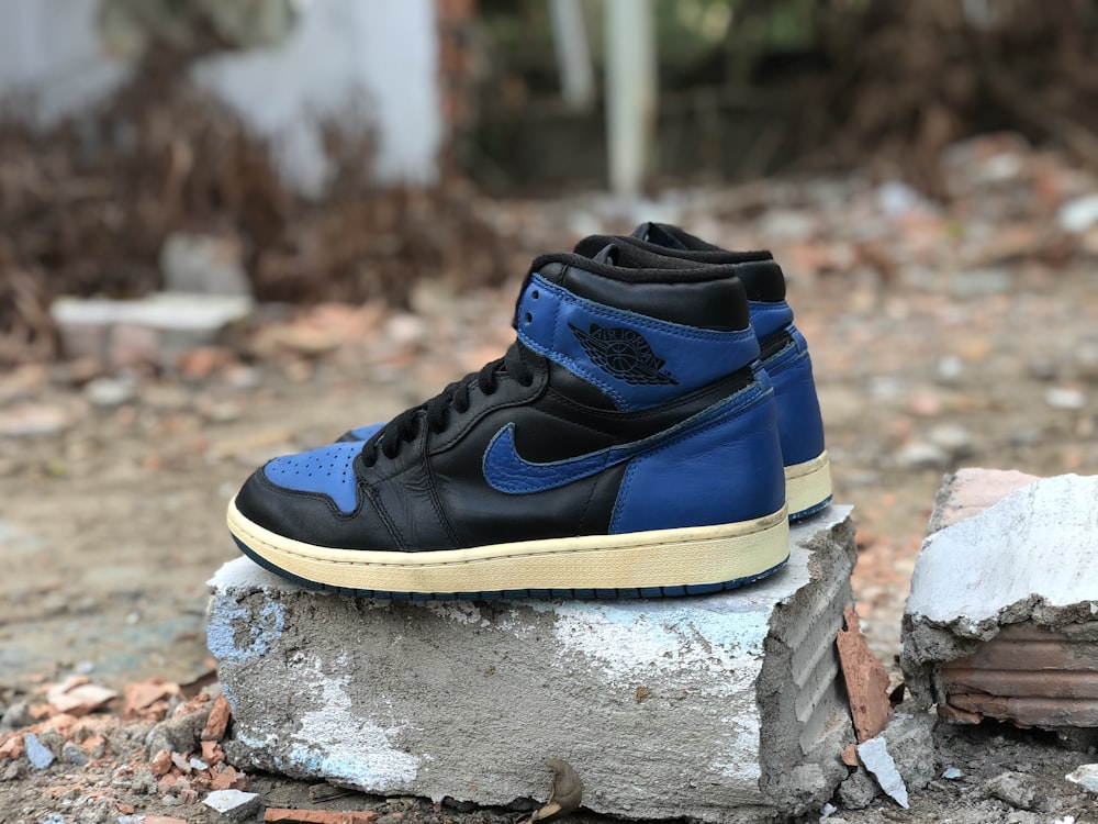 a pair of blue and black sneakers sitting on a rock