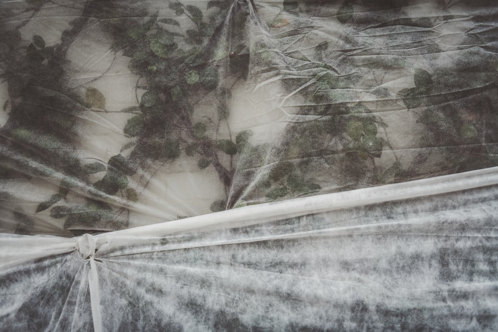 a bed covered in a white sheet with trees on it