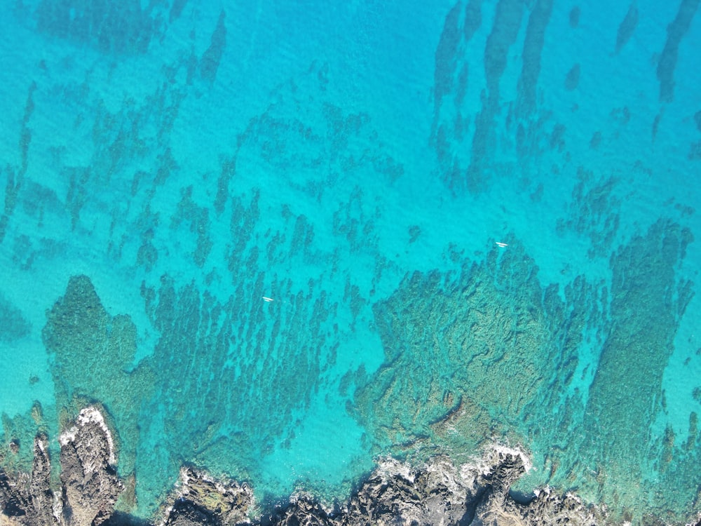 an aerial view of the ocean and rocks