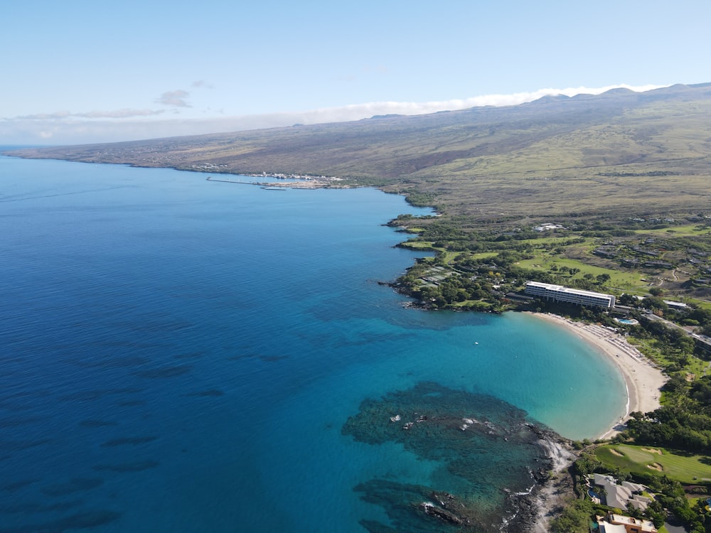 a large body of water next to a lush green hillside