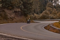 A rider leaning into a sharp turn, the Blue Ridge Mountains rising behind.