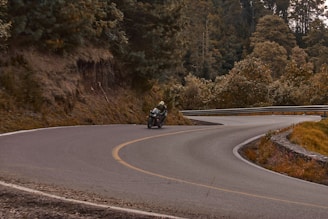 A rider leaning into a sharp turn, the Blue Ridge Mountains rising behind.