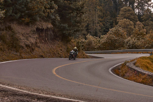 A rider navigating a smooth twisty road surrounded by citrus orchards with mountain backdrop.