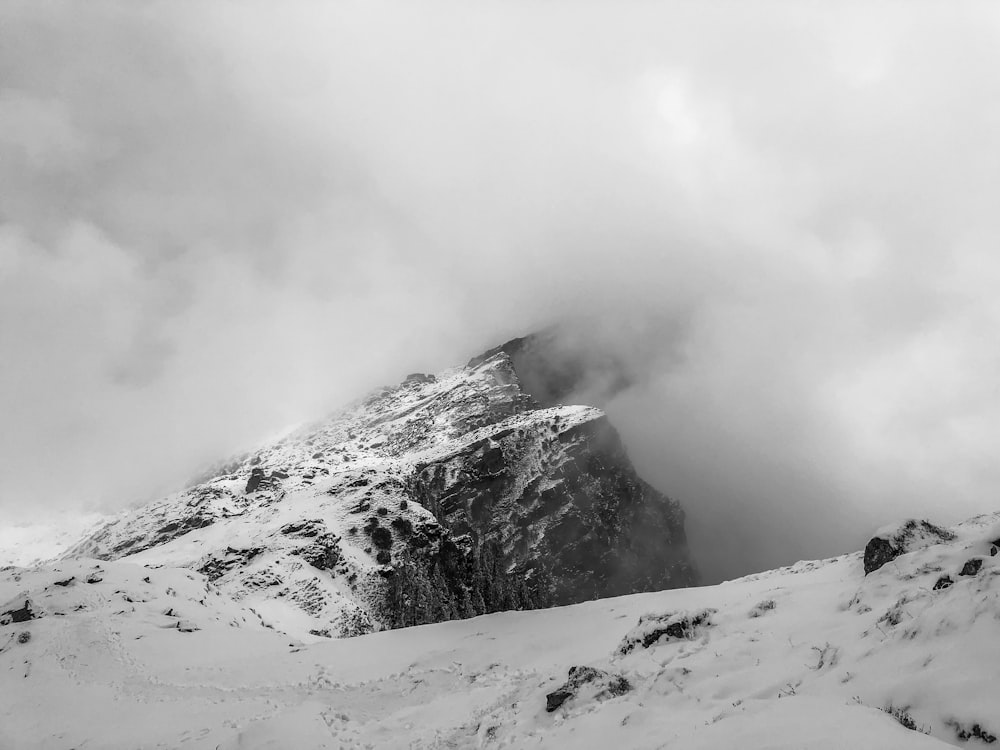 a mountain covered in snow and clouds on a cloudy day