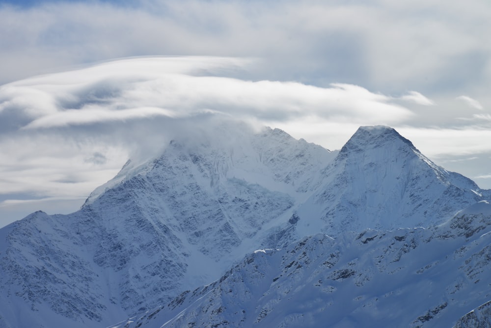 a mountain covered in snow under a cloudy sky