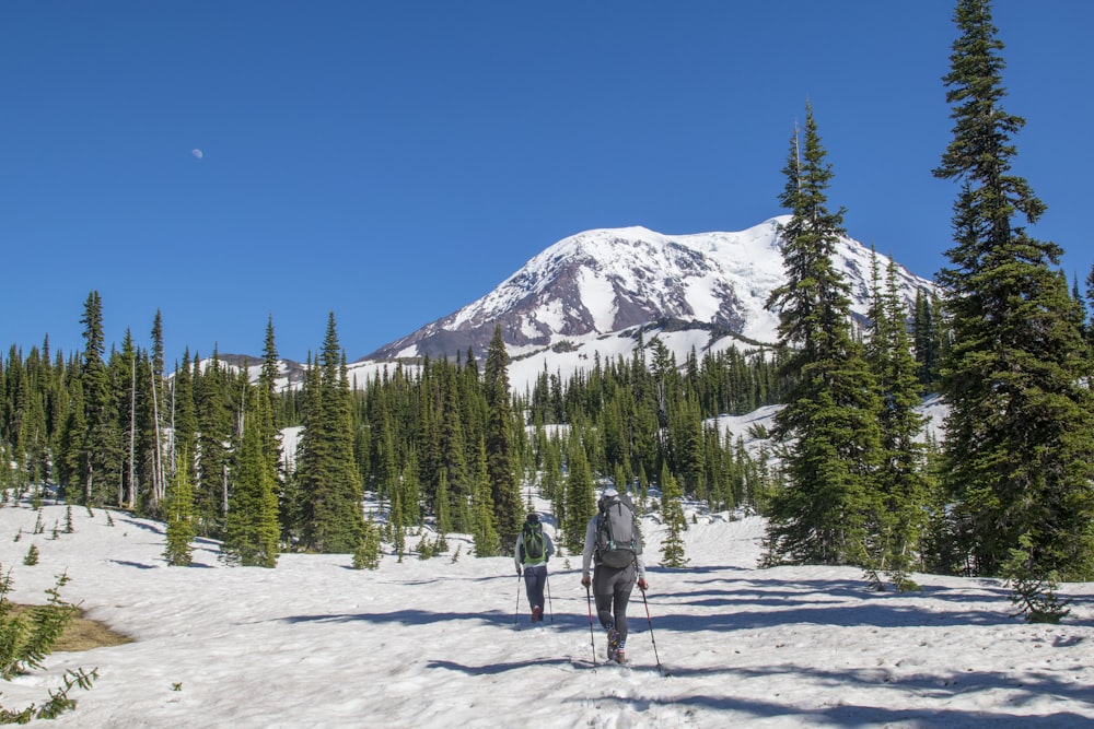 a couple of people walking across a snow covered field