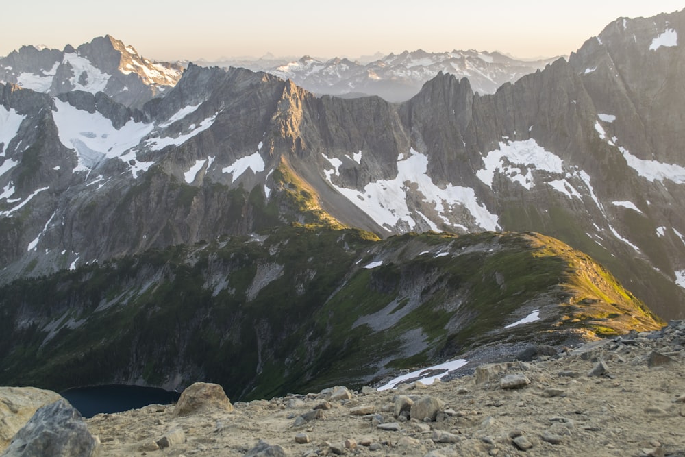 a man standing on top of a mountain next to a lake