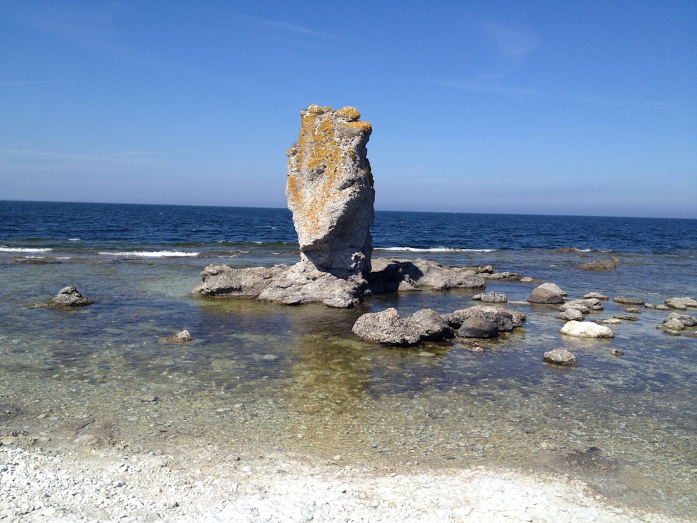 a large rock sitting on top of a beach next to the ocean