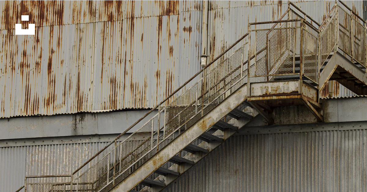 A metal staircase going up to a rusted building photo – Free Rust Image ...