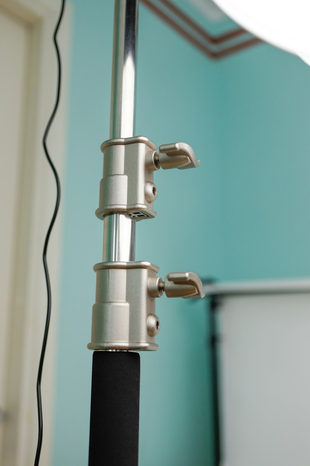 a close up of a metal pole with a white toilet in the background