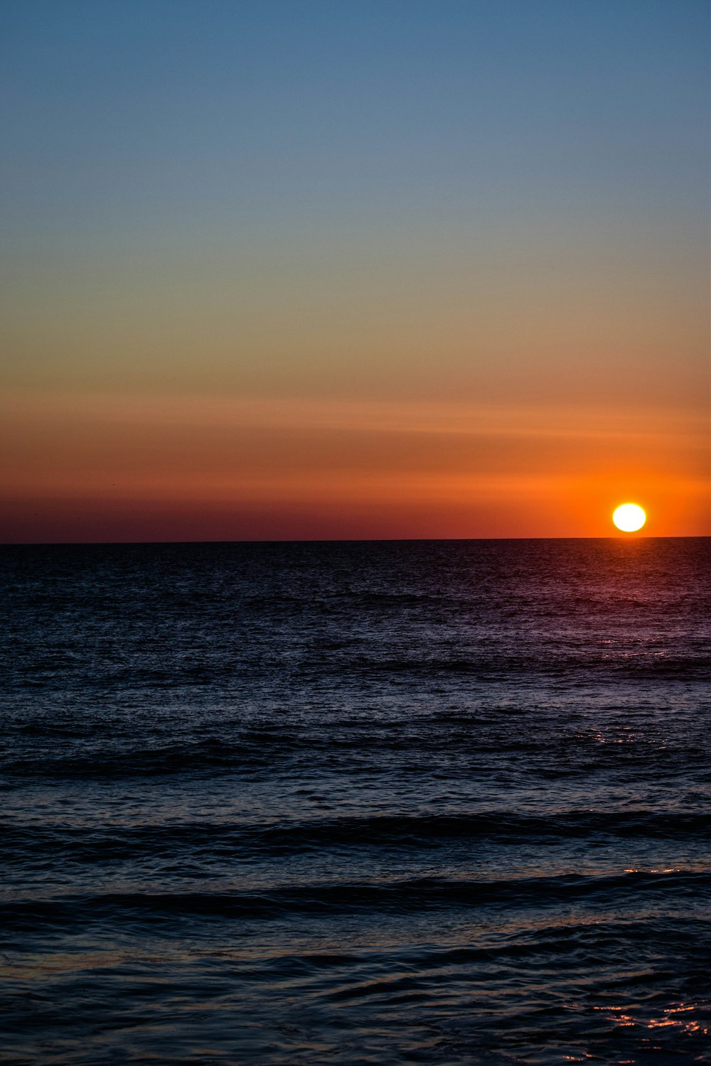 the sun is setting over the ocean on a clear day