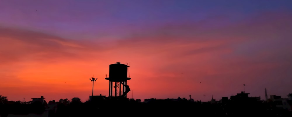 a silhouette of a water tower against a sunset