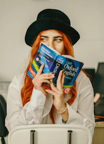 a woman with red hair is holding a book