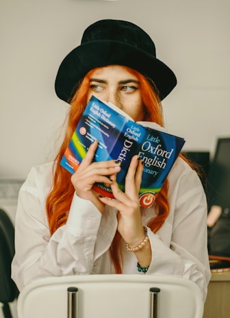 a woman with red hair is holding a book