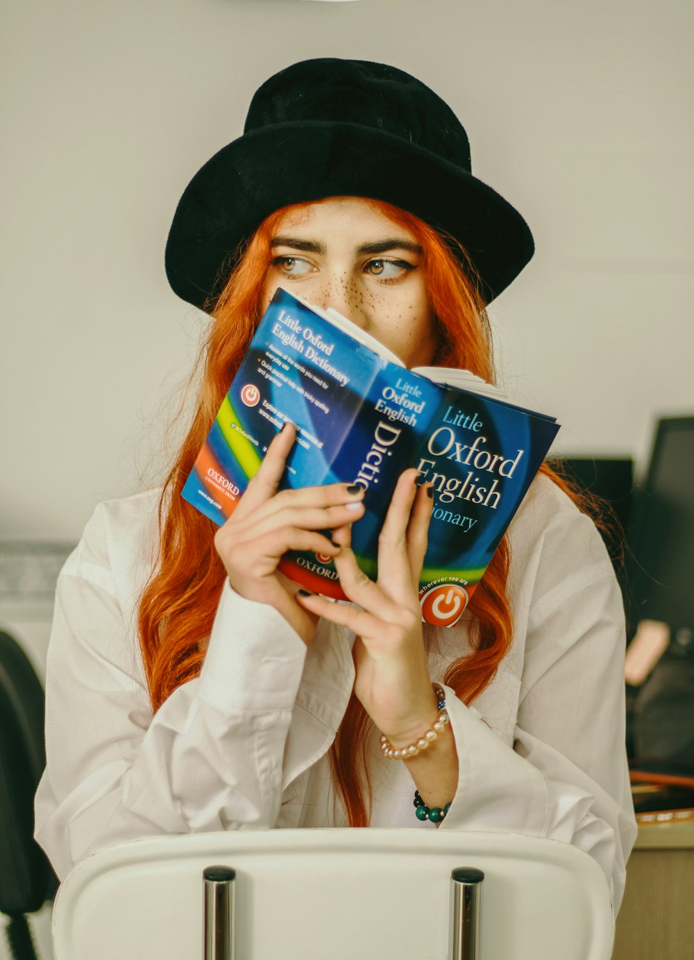 a woman with red hair is holding a book
