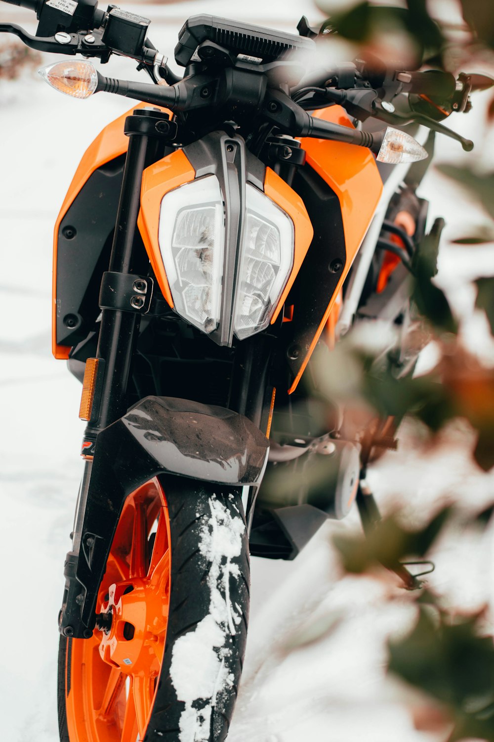 an orange and black motorcycle parked in the snow