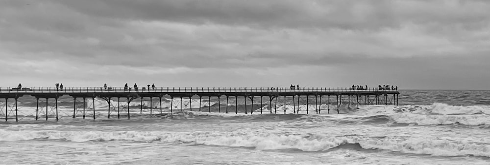 a black and white photo of people on a pier