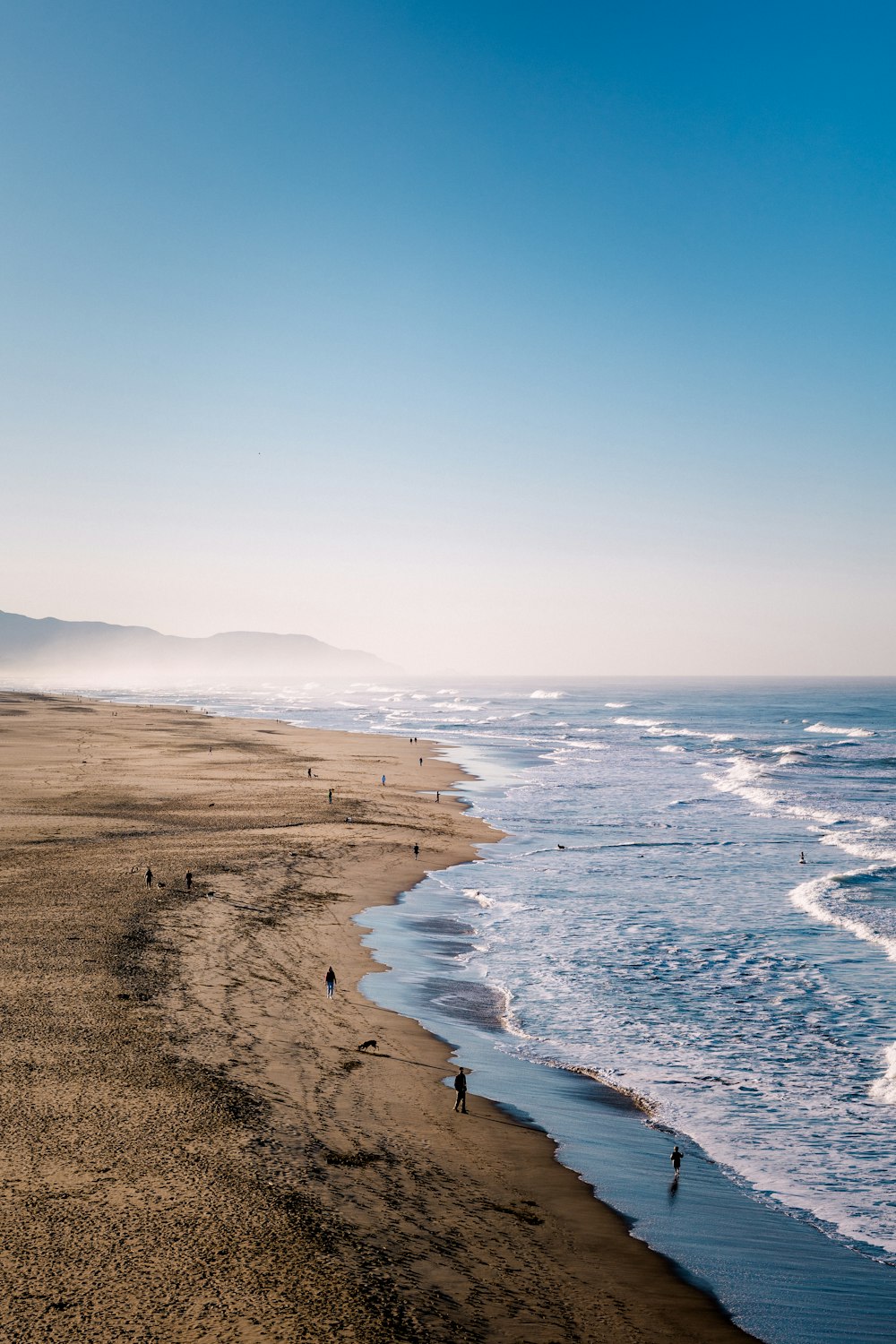 a group of people walking along a beach next to the ocean