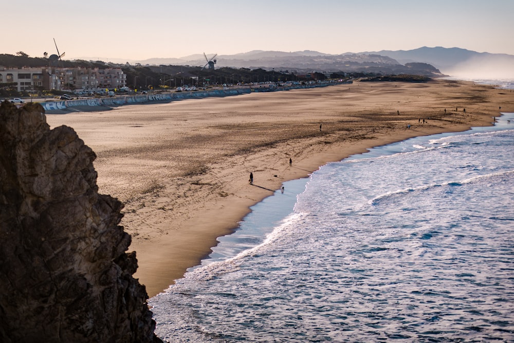 uma praia de areia ao lado do oceano com pessoas andando sobre ela