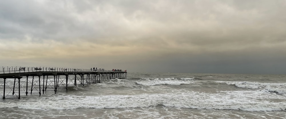 a pier on the beach with waves crashing in front of it