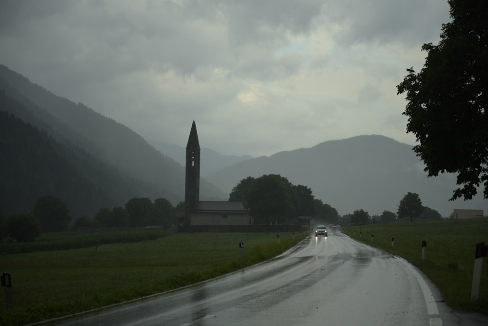 a wet road with a clock tower in the distance