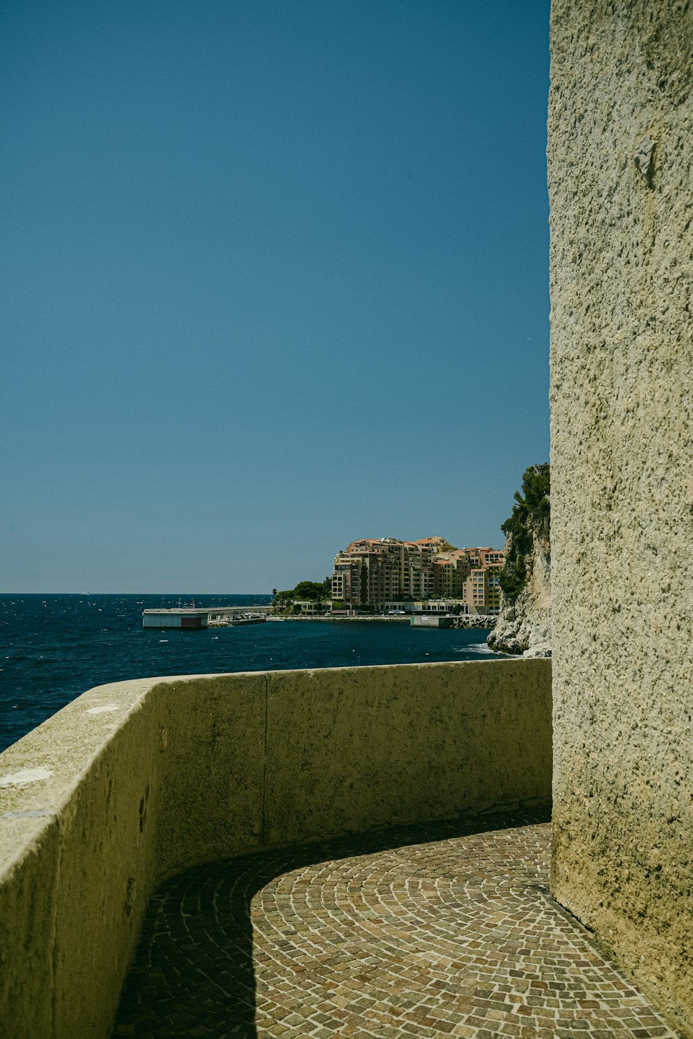 a bench sitting on top of a stone wall next to the ocean