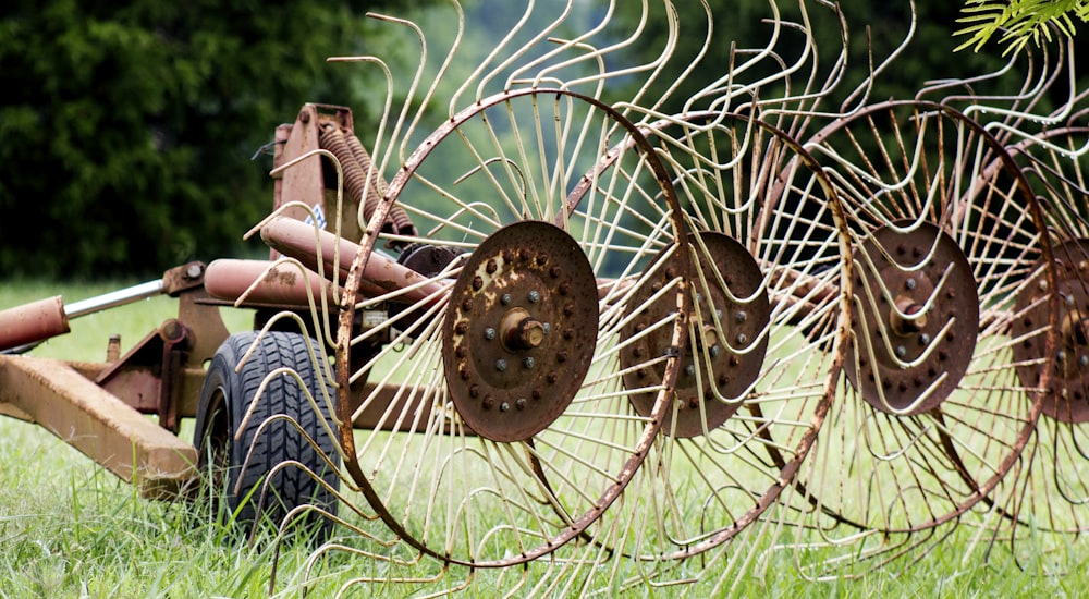 a row of old farm equipment sitting in the grass