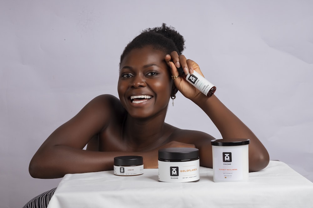 a woman sitting at a table with some skin care products