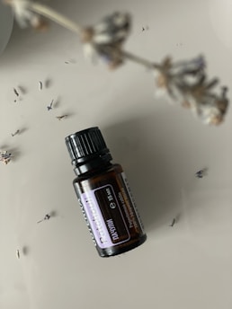 Bottles of golden patchouli oil arranged on a wooden table with fresh leaves.