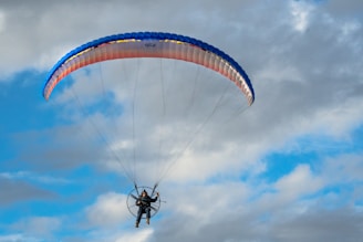 a person is parasailing in the air on a cloudy day