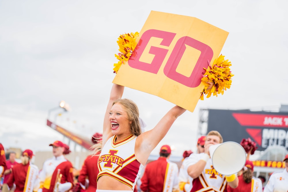 eine Cheerleaderin, die ein Schild in die Luft hält