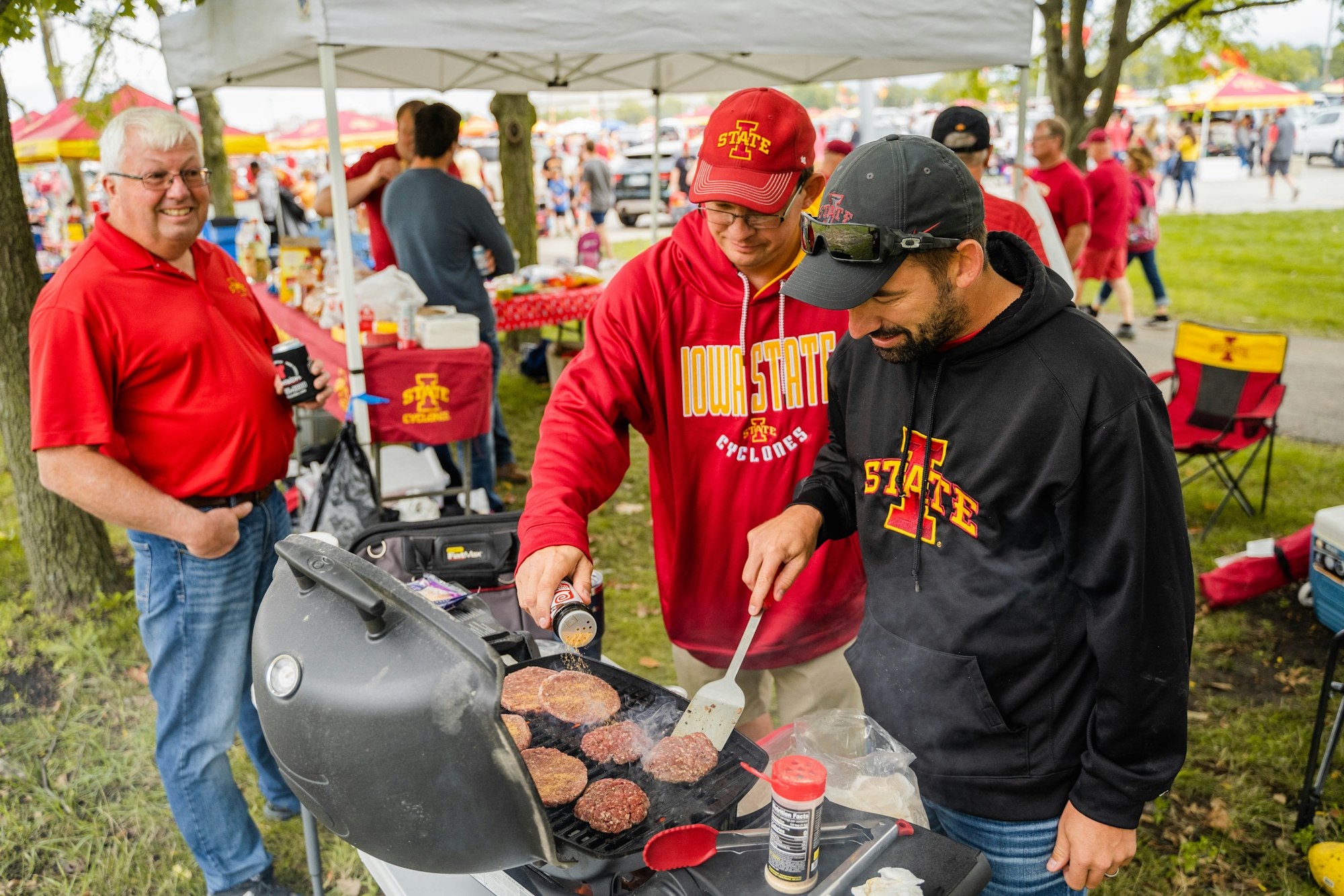 Iowa State fans grill burgers during a tailgate at a football game.