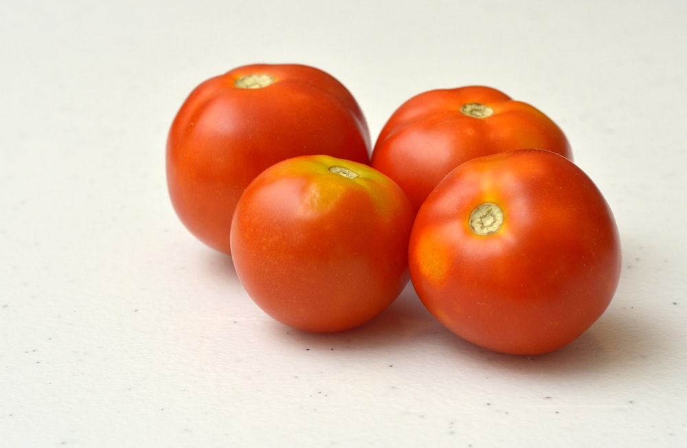 a group of four tomatoes sitting on top of a table
