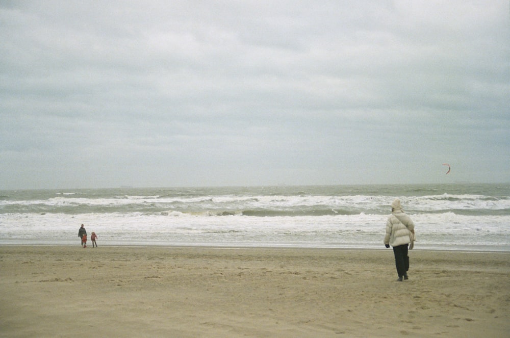 a person standing on a beach flying a kite