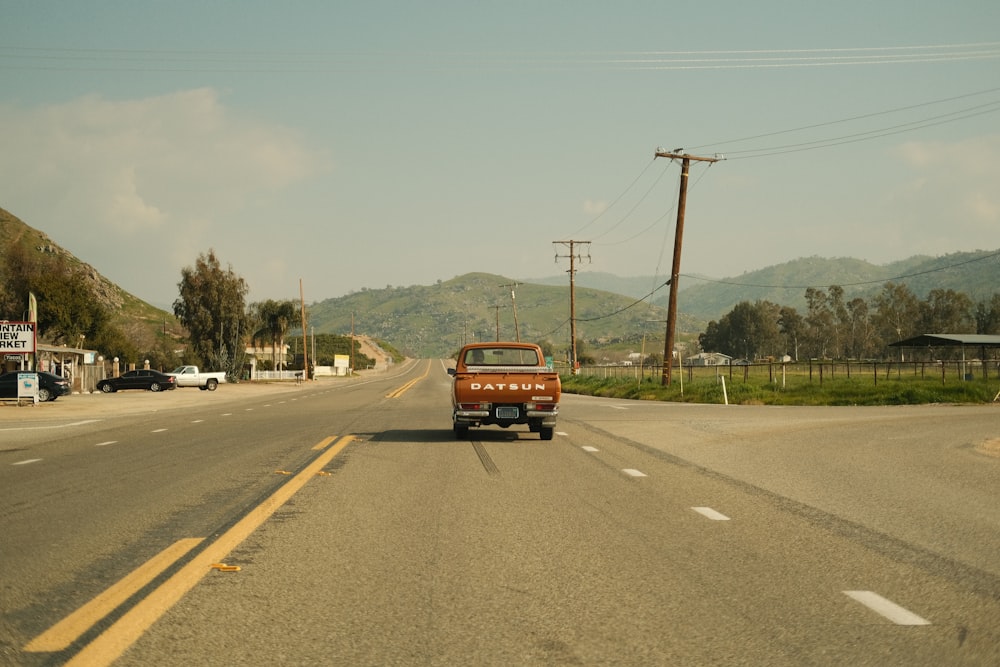 an old truck is driving down the road