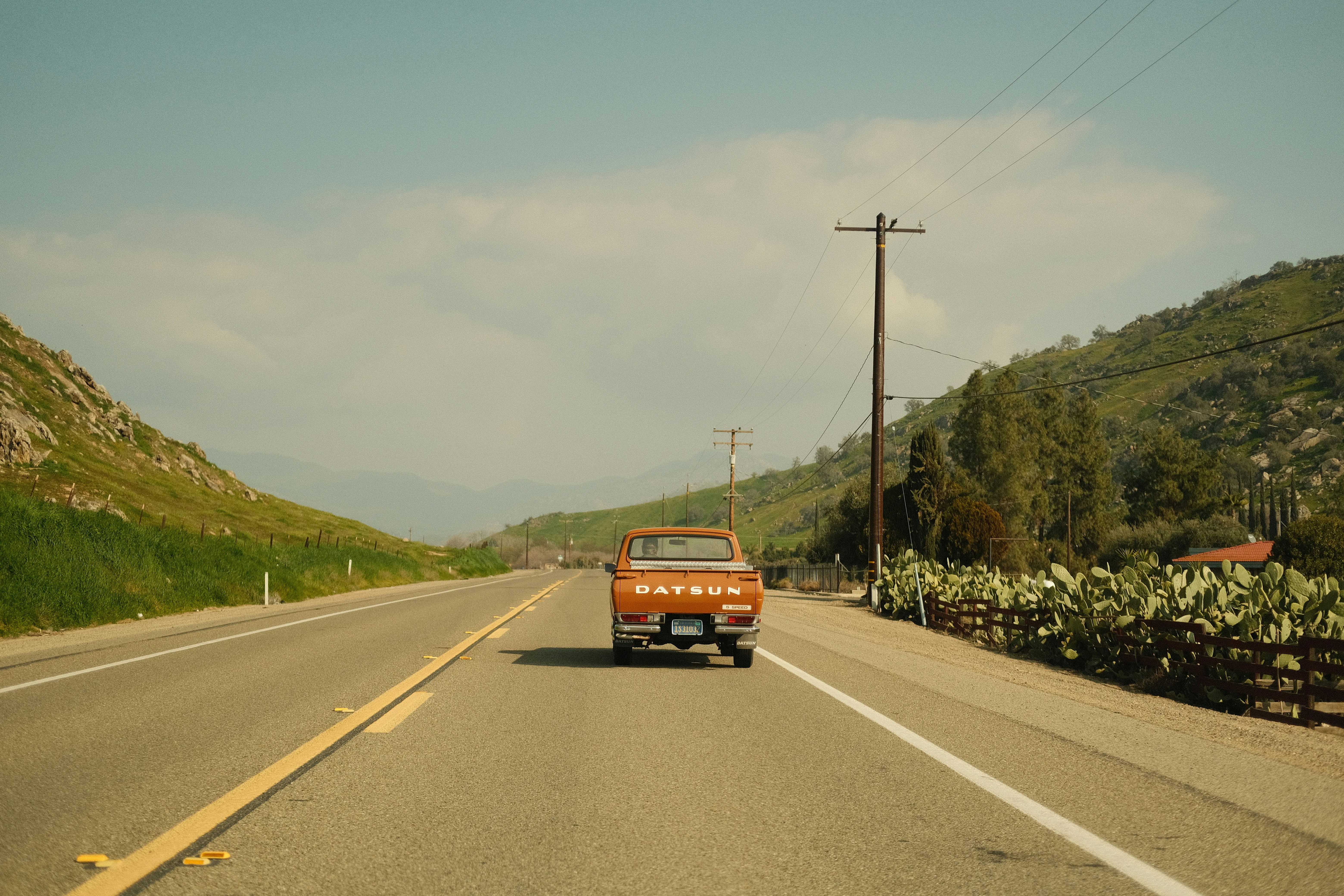 a van driving down a road next to a lush green hillside