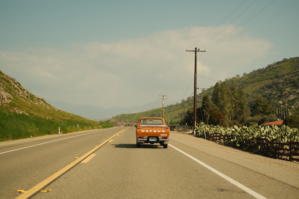 a van driving down a road next to a lush green hillside