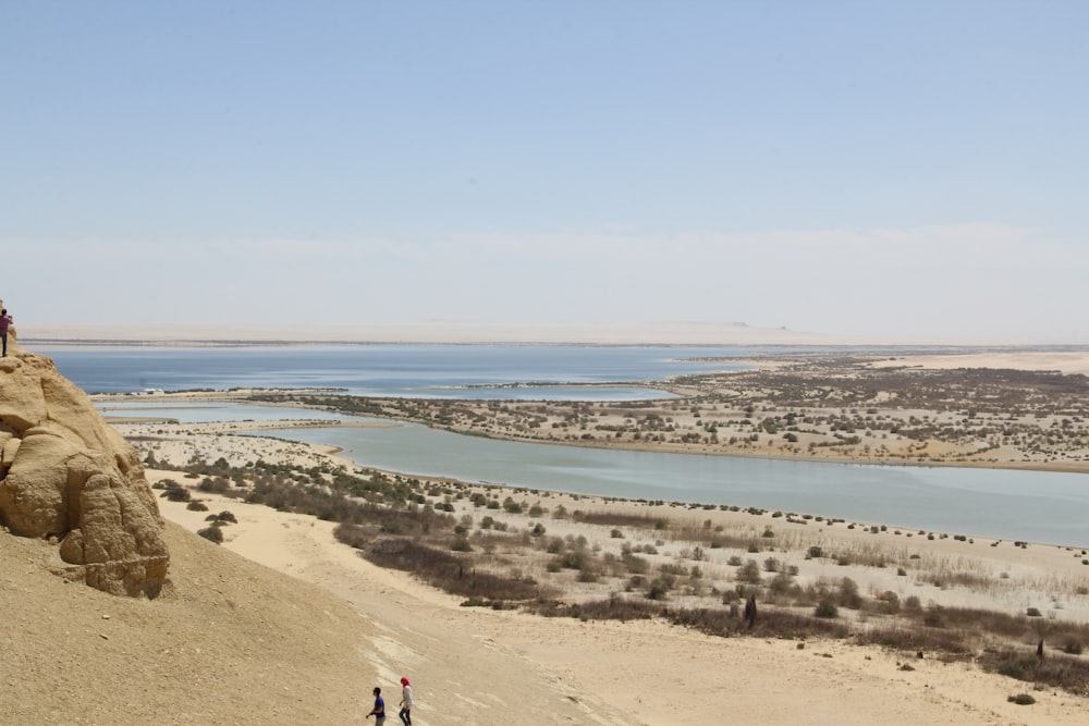 two people standing on top of a hill overlooking a lake