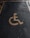 A yellow wheelchair symbol painted on a dark asphalt parking space.