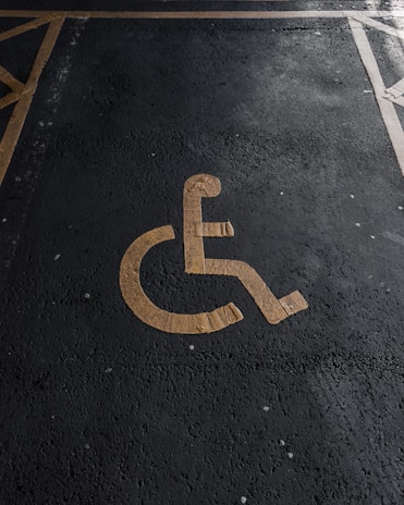 A yellow wheelchair symbol painted on a dark asphalt parking space.