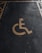 A yellow wheelchair symbol painted on a dark asphalt parking space.