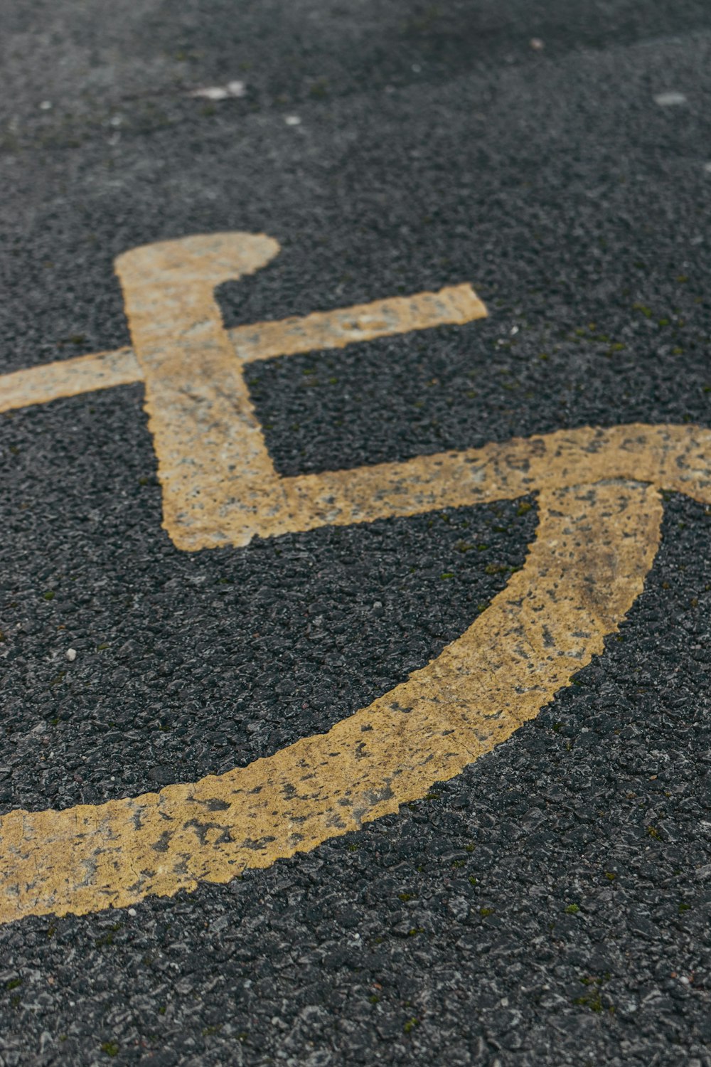 a handicapped sign painted on the asphalt of a street