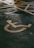 A painted yellow symbol on a textured asphalt surface representing a wheelchair-accessible parking space. The background shows part of a grid of yellow lines indicating the parking area.