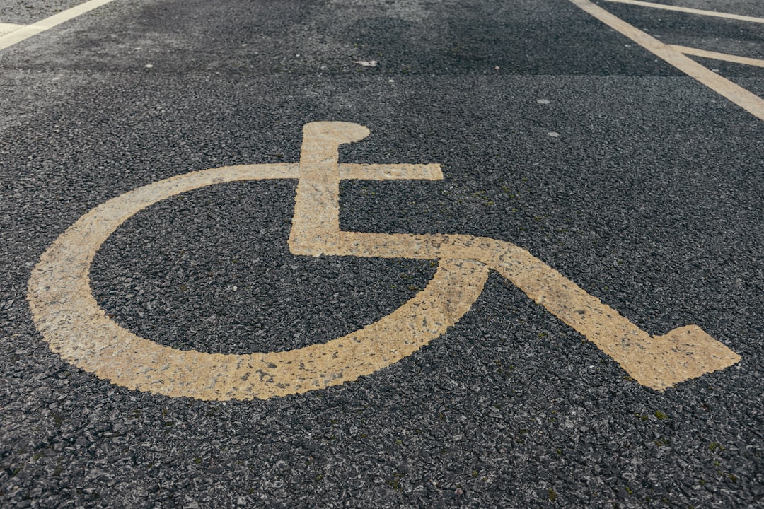 a handicapped sign painted on the pavement of a parking lot, Disabled parking. Accessible parking spot. Blue badge. Yell