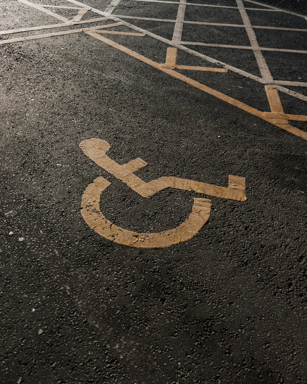 a handicapped sign painted on the asphalt of a parking lot