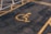 A parking lot features a yellow painted symbol on the ground indicating a reserved space for disability access. The asphalt is dark and slightly worn, with parallel yellow lines creating a distinct parking area.