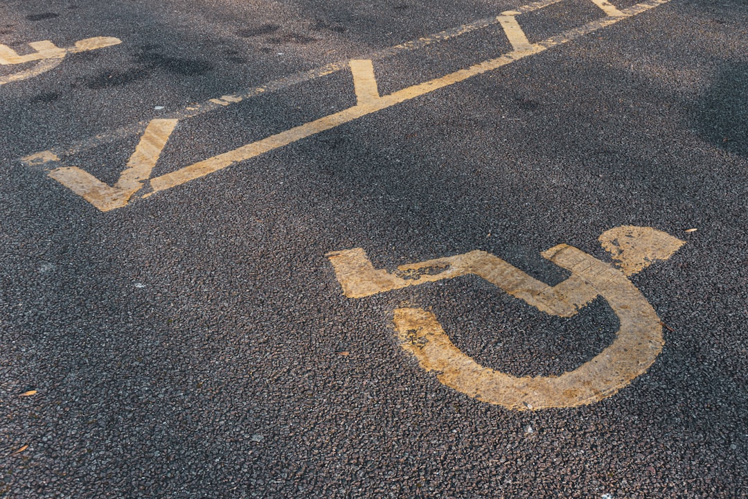 a handicapped sign painted on the asphalt of a parking lot, Disabled parking. Accessible parking spot. Blue badge. Yello