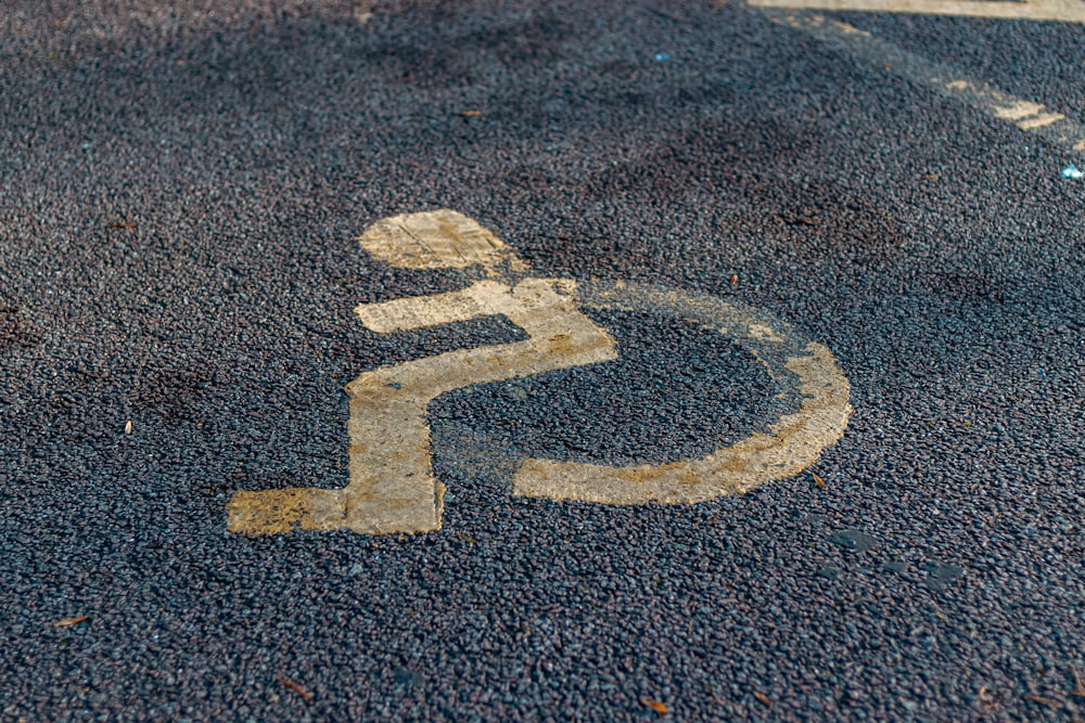 a handicap sign painted on the asphalt of a parking lot