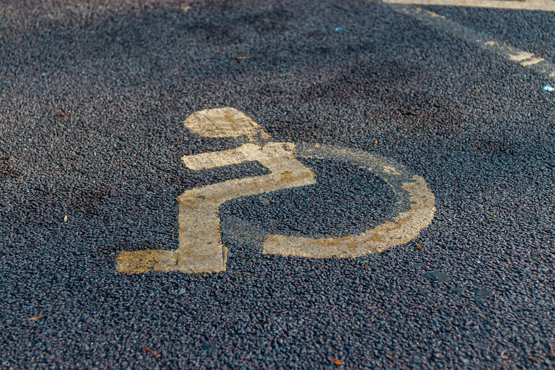 a handicap sign painted on the asphalt of a parking lot, Disabled parking. Accessible parking spot. Blue badge. Yellow w